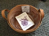Top-down view of Longaberger Button Basket showing leather handles and clear liner with original literature inside.