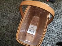 Top-down view of rectangular woven Longaberger basket with handle, showing inside bottom with 019 tag.