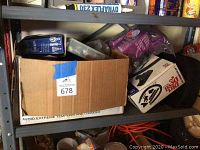 View of the utility shelf showing the lower two shelves with boxes, coiled extension cords, and cans.