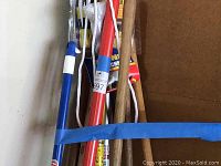 Tools bundled together with blue tape showing handles of hoes, rakes, and other garden tools.