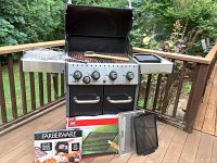 Front view of Broil King Baron grill with accessories on deck. Shows overall grill condition and included items.