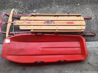 Top view photo showing Flexible Flyer III wooden sled and adjacent red Slim Sled on concrete