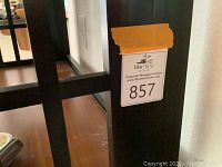 Close-up of bookshelf frame showing auction tag and dark finish.