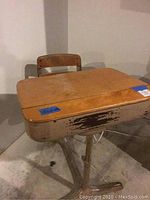 Vintage school desk with attached chair showing worn wooden top and solid body with worn paint on metal base.
