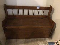 Front view of wooden bench with backrest and hinged seat closed.