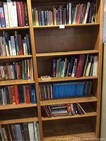 Books arranged on wooden bookshelves, showing a variety of titles and book sizes