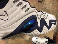 Close up of lateral side showing white leather, navy detail, and shiny blue cushioning pod of Nike Air Zoom Flight Five shoe.