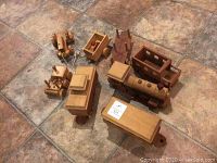 Overview of wooden train set and various pull toys on tiled floor, showing locomotive, train cars, and animal pull toys.