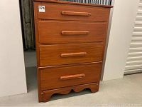 Front view of the four drawer wooden dresser showing finished wood surface and drawer handles.