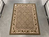 Top-down photo of a rectangular area rug showing diamond grid center pattern and floral border.