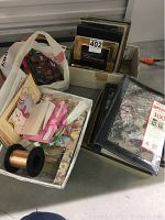 Photo showing assortment of photo frames, albums, ribbons, and stationary items organized in boxes and bags on floor.
