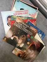 Stack of vintage Christmas vinyl record albums featuring Barbara Streisand, Nat King Cole, Elvis Presley, and others, visible cover artwork and titles.