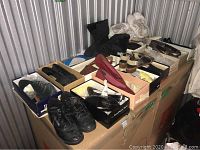 Overview of assorted women's shoes in boxes on storage shelf, showing various styles and colors including black, white, red, and metallic shoes.
