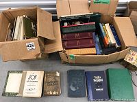 Two boxes filled with assorted vintage books laid on the floor, showing green and maroon hardcovers, including Birds of America and others.