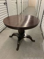 Front view of the round mahogany wood dining table showing pedestal base with four legs and dark polished finish