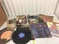 Nine assorted vinyl record albums including Pink Floyd, Disney, polka, and others displayed on the floor with one record out of sleeve.