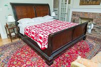 Full assembled bed frame in bedroom, front angled view showing headboard, footboard, side rails with bedding removed
