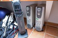 Two Kenwood oil-filled heaters and one Bionaire standup heater grouped together on floor tiles under a shelf.