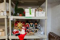 Shelf with wooden nutcracker statues, Santa plush figures, Christmas star ornament, snow globes, and boxes of decorations