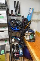 General overview of lot on metal shelving and bench showing helmets, vests, boots, rackets, ski clothing bag, foam mat and stability ball