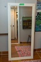 Full front view of rectangular floor mirror with white textured diamond pattern frame and beveled edges.