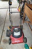 Front view of red Homelite electric lawn mower with handle folded down, showing overall condition and wheels.