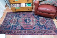 Indoor view of a dark blue and red geometric tribal runner laid on tiled floor next to leather chair and drawer unit