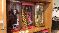 Three Barbie dolls in original boxes displayed on shelf: Chilean, Chinese, and Thai costumes.