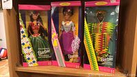 Three boxed collector Barbie dolls including Polynesian, French, and Ghanaian cultural costumes.