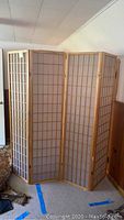 Full view of the assembled four-panel wooden folding screen in a room, showing its height and foldable structure.