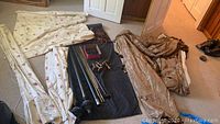 Overview of all fabric window treatments and some accessories laid on floor.