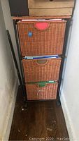 Front view of the 3 drawer wicker filing cabinet showing colored handle pulls and metal frame.