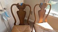 Four wood dining chairs together showing panel backs and woven wicker seats.