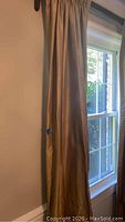 Single gold silk drapery panel hanging, showing sheen and length against window.