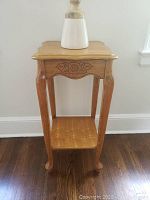 Carved wood telephone table with floral detail shown on hardwood floor.