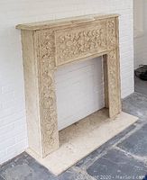 Front view of faux marble fireplace mantel surround and matching hearth base against white brick wall