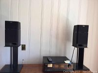 Front view of the two Sony SS-H4700 speakers on stands and the Onkyo TX-SR501 receiver placed on a wooden surface
