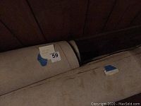 Two rolled rugs with a lot number tag indicating 59, the rugs are rolled and not showing pattern clearly