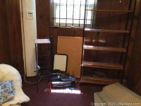 Photo of office set including metal-framed basket storage rack, shelving unit, whiteboard, bulletin board, VCR and other items on the floor