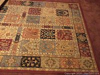 Top view of the patchwork patterned area rug showing floral and geometric motifs in multiple colors including brown, beige, blue, black, and red.