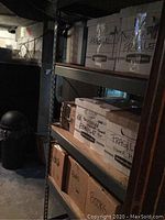 Grey metal shelving unit loaded with cardboard boxes against a basement wall