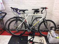 Side view of two bikes mounted on rack against white brick wall