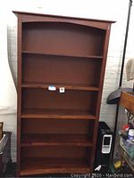 Front view of the solid wood bookshelf with 6 shelves and curved top edge.