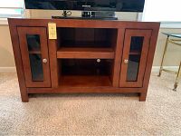 Front view of the honey finished TV stand cabinet showing two glass-door cabinets on sides and central shelving space.