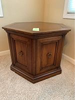 Wood hexagon-shaped drum table with paneled sides, two doors with metal ring pulls, seen from front angle.