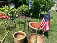Photo showing garden pots, shepherd's hooks, American flag, and metal garden decor with solar lights
