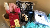 Connoisseurs jewelry cleaning kit with box, cleaning solution bottle, cleaning cloth, black hair dryer, and folded shower curtain with hooks set out on table.