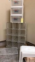Photo showing stacked clear plastic storage drawers on top of the 15 compartment shoe rack with white plastic mesh cubbies and metal connectors