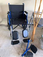 Front view of black and blue wheelchair with padded leg rests, footplates, and folding frame
