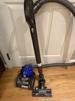 Assembled vacuum with canister, hose, wand and floor head on wood floor